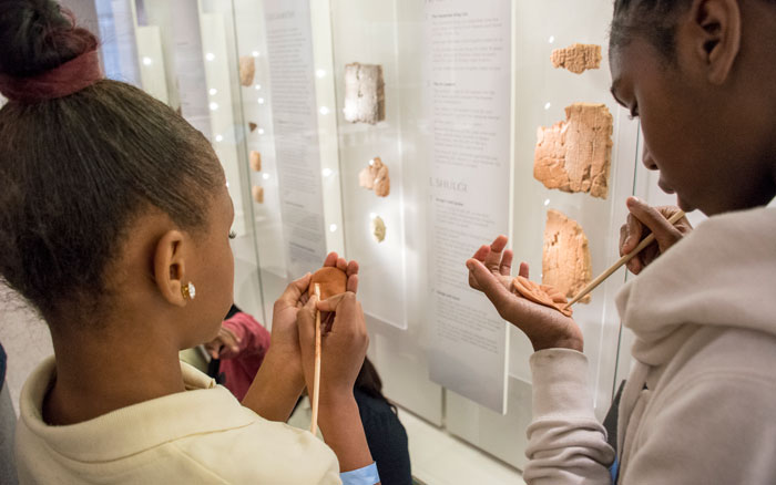 Two students learning to write in cuneiform in the Middle Easter Galleries.
