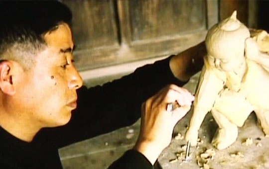 Man sculpting clay figure.