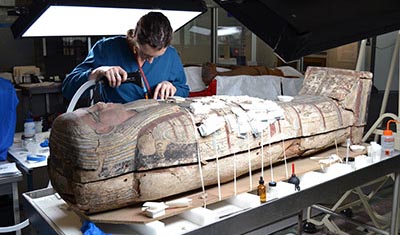 Archaeologist examining Egyptian mummy.